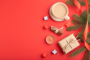 Obraz na płótnie Canvas Christmas or New Year composition. Decorations, box, fir and spruce branches, cup of coffee, on a red background. Top view, copy space.