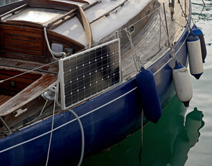 Un pannello solare montato su una barca a vela di legno con lo scafo blu. 