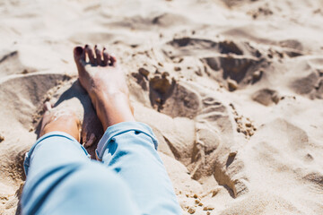 Woman tanned legs on sand beach. Travel concept.