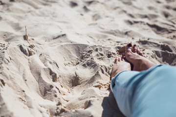 Woman tanned legs on sand beach. Travel concept.