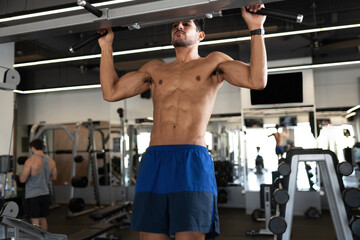 Fototapeta na wymiar Young man doing pull up exercises at the gym