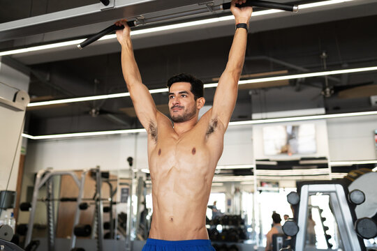 Muscular man hanging on a gym machine
