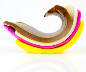 Elastic ribbons of colorful candy taffy on a reflective surface.