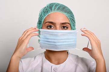 Enfermera mirando al frente, se pone una mascarilla quir&uacute;rgica
