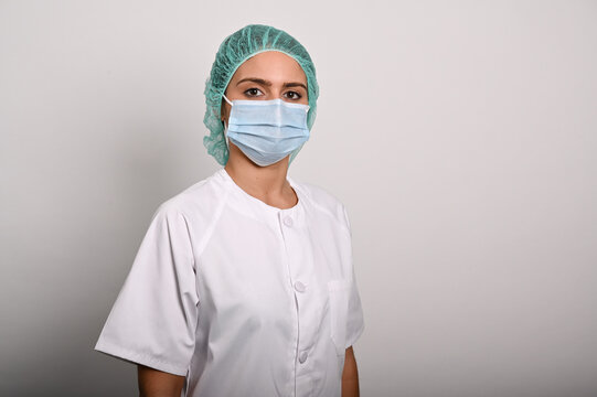 Enfermera posa de lado con una mascarilla quirúrgica y gorro