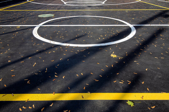 basketball area in circle on the marking playing field with asphalt tarmac, sports  lit by sun light on playground with copy space, nobody.