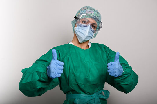 Enfermera protegida con traje (EPI), gafas y mascarilla, tiene los dos pulgares arriba
