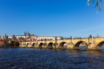 Obraz premium Autumn colorful Prague Lesser Town with gothic Castle and Charles Bridge above River Vltava in the sunny Day, Czech Republic