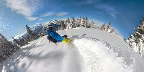 SELFIE: Snowboarder is carving fresh powder snow while riding through a forest