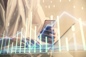 Double exposure of financial graph sketch hologram and woman holding and using a mobile device. Stock exchange concept.