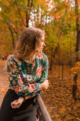 A cheerful girl stands leaning against a white railing, a young blonde with a lovely smile in a colored shirt, having intelligence on the background of the steps autumn glitter trend