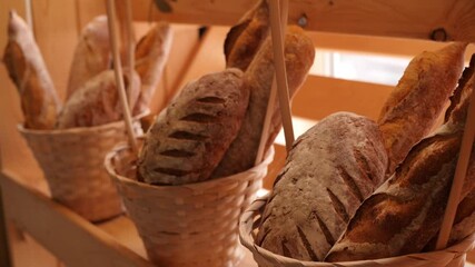Breads and baked goods large assortment in decorative baskets on wooden bakery shelves in background slow motion medium shot in 4K