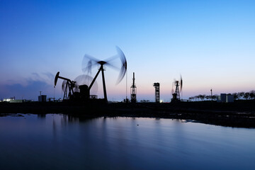 Fototapeta premium the oil pump in the evening, the evening silhouette of the pumping unit, the silhouette of the oil pump