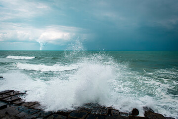 Fototapeta na wymiar strong splash wave on rocks in the Mediterranean sea during the storm with tornado background