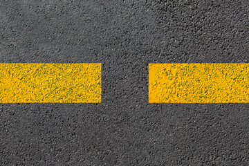 two yellow dashed line of road markings close-up on the new bituminous asphalt road surface top view of grainy tarmac highway, nobody.