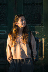 Portrait of young woman stands on the street at sunset.