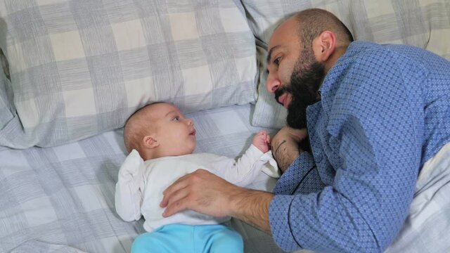 Close up of father and his newborn baby making video call to mother or relatives in a bed. Concept of technology, new generation, family