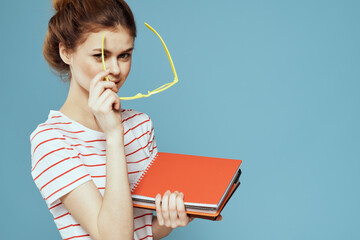 Beautiful female student with notepads and in yellow glasses on a blue background education science...
