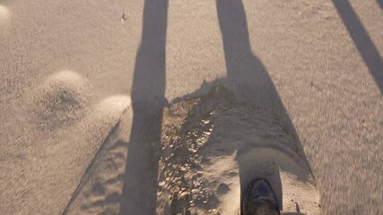 This POV video shows boots sliding through a deep sandy terrain.