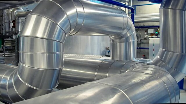 Slider shot of large industrial tubing and piping inside central heating plant