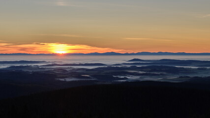 Inversion in the valley during sunrise with mountain ridge in the background.