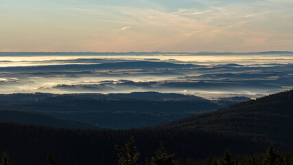 Sun light rays during sunshine peaking through morning mist on a wavy landscape.