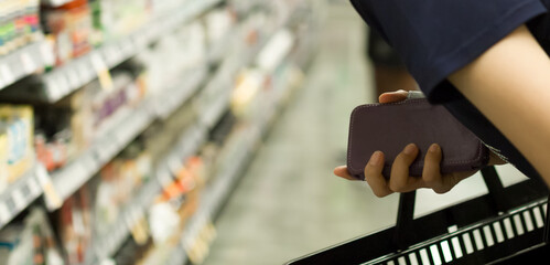 Woman Shopping at Grocery Market Pharmacy. Supermarket Shopper Doing Groceries. Female Holding Basket Trying to Decide which Products to Buy. Retail Healthcare Medicine, Vitamins, and Supplements.
