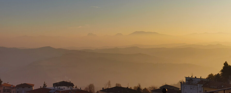 Vista sui monti Appennini valli e colline in un tramonto  di nebbia e foschia colore arancio