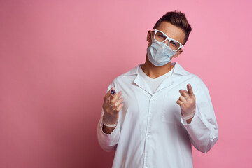 A doctor in a medical mask and gloves holds a syringe in the hands of an injection laboratory