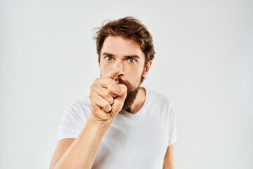 Fototapeta na wymiar Bearded man gesturing with hands cropped view white t-shirt studio emotion light background