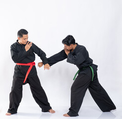 two Asian men wearing pencak silat uniforms to fight on a white background