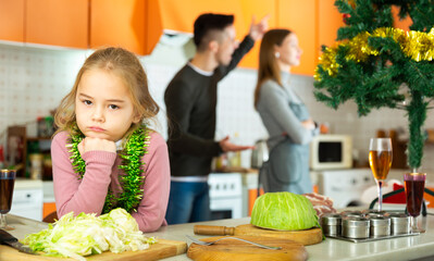 Frustrated daughter suffering from mother and father conflicting at home kitchen at christmastime