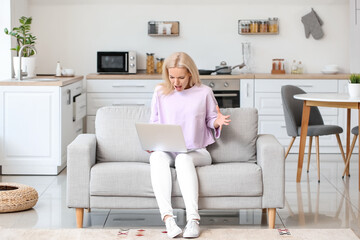 Fototapeta premium Stressed young woman with laptop at home