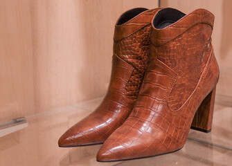 brown leather boots.
Brown leather ankle boots on the right on a glass shelf with space for text on the left, side view close-up.