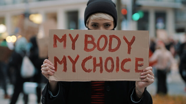 Woman holding a sign My Body, My Choice. Protest against tightening of the abortion law . Nationwide women's strike. Wearing protective face mask against COVID-19 Coronavirus. High quality photo