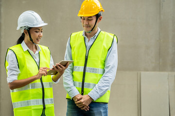 Asian young female engineer explaining job on tablet to male worker.