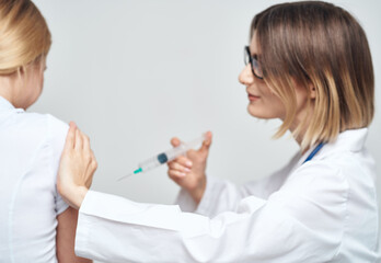 A woman doctor in a medical gown is giving an injection to a patient