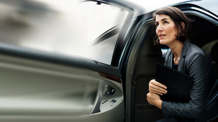 Businesswoman getting out from a car - obrazy, fototapety, plakaty