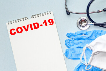 The word COVID -19 . Medical concept. the medicine NOTEBOOK, GLOVES, PROTECTIVE MASK, STETHOSCOPE ON THE TABLE Medical concept. the medicine