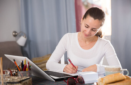 Young woman sitting at table at home calculating domestic finances. High quality photo