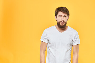 Obraz premium Bearded man in a white T-shirt gestures with his hands emotions studio yellow background