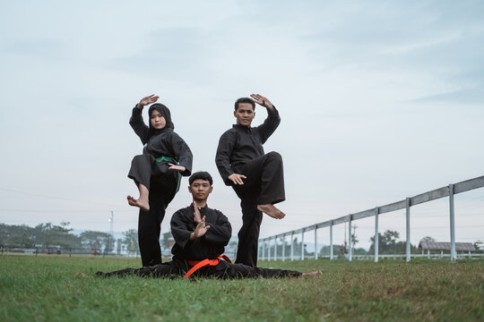 three Asians wearing pencak silat uniforms with formations on outdoor background