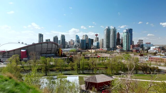 Aerial flying over the Calgary skyline near the Saddledome in the Summer with blue sky and clouds.