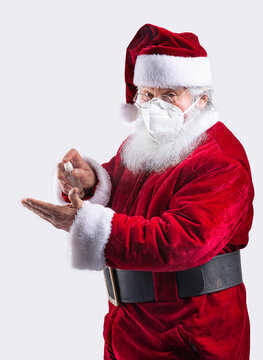 Santa Claus cleaning hands with gel, preventing covid in white background wearing a mask