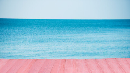 Fototapeta na wymiar Pink wooden floor of swimming pool with sky and sea