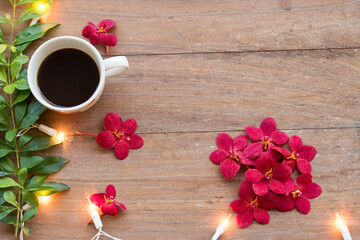 hot coffee with red orchid and decorate light for lifestyle in winter season arrangement flat lay style on background wooden