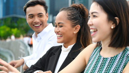 Three asian young friends standing outdoor in the city talking, smiling  and enjoying city life