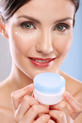 Face beauty portrait of woman with natural skin holding cream jar.