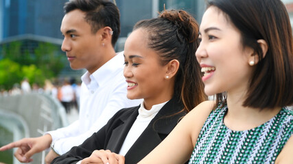 Three asian young friends standing outdoor in the city talking, smiling  and enjoying city life