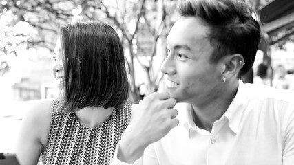 Young asian couple relaxing outdoor at a restaurant table